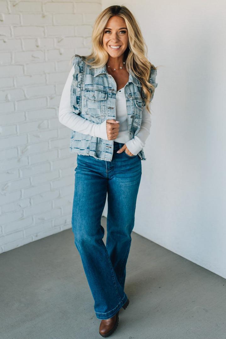 Woman wearing a denim checkered vest over a white shirt against a plain background