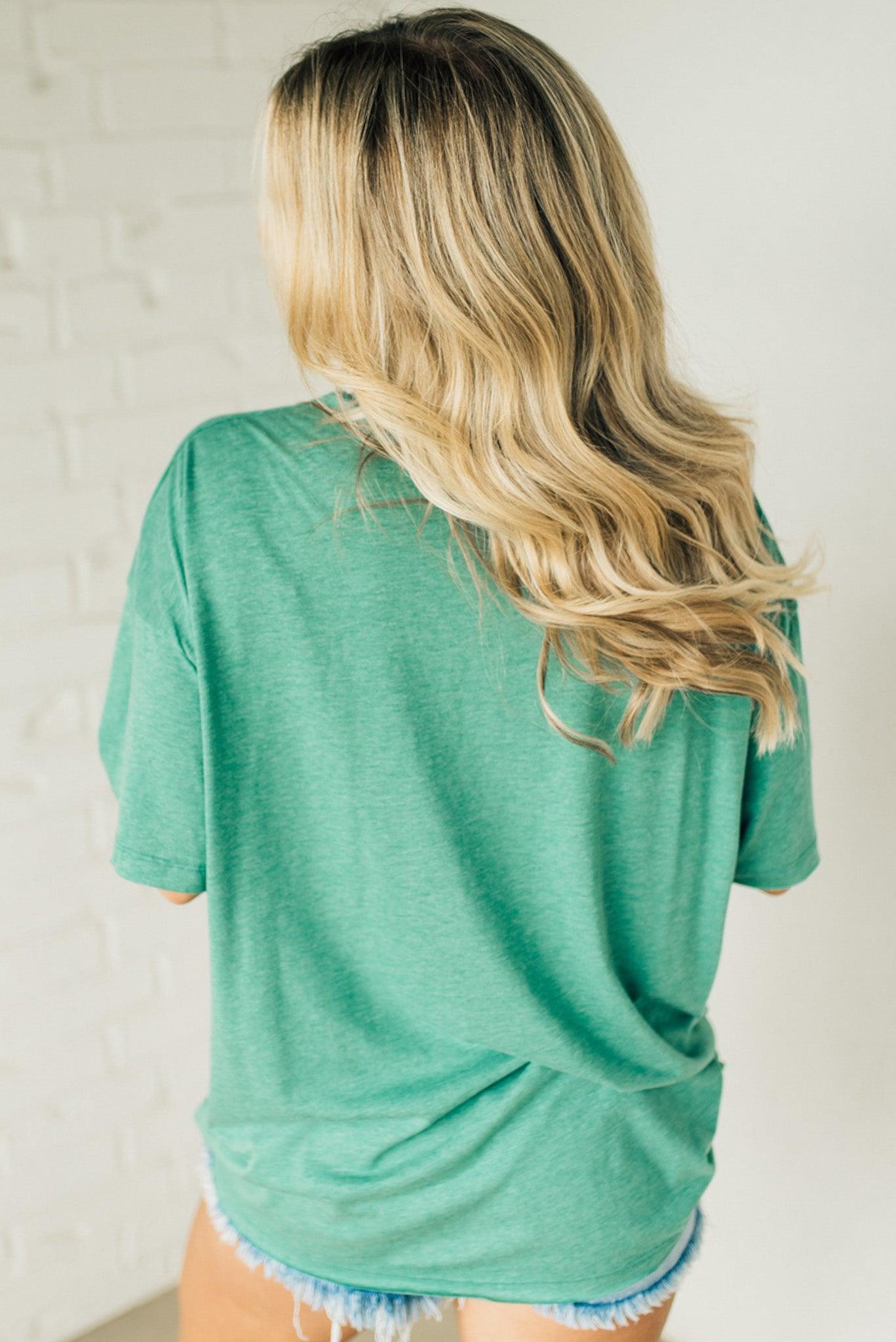 Blonde woman wearing an oversized solid tee with front pocket, and raw scissor cut edges.