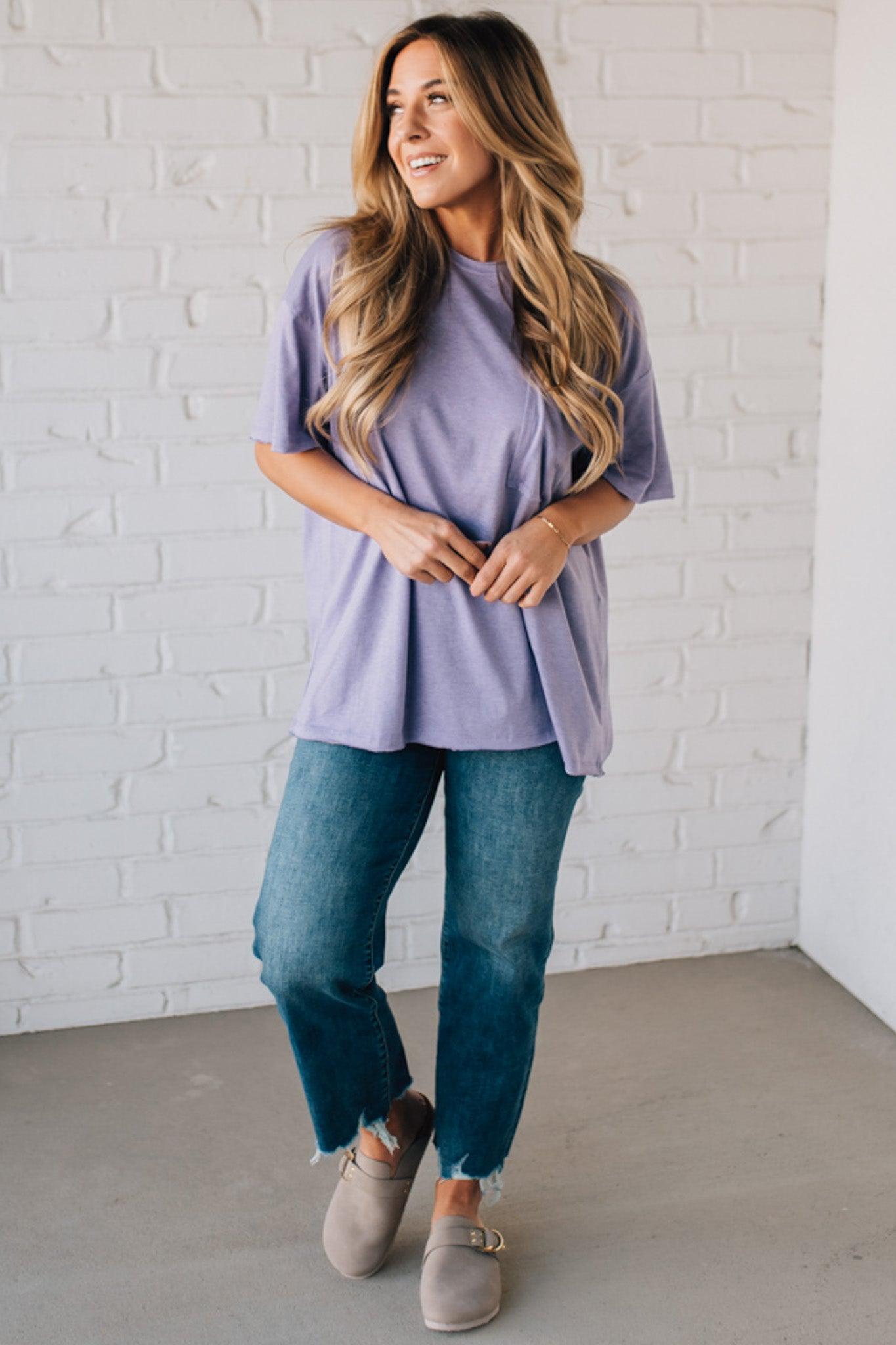 Blonde woman wearing an oversized solid tee with front pocket, and raw scissor cut edges.
