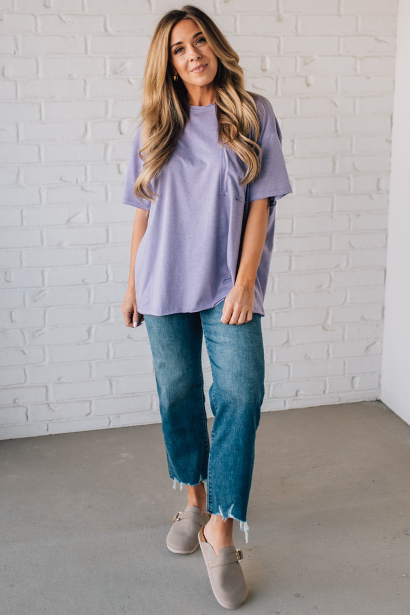 Blonde woman wearing an oversized solid tee with front pocket, and raw scissor cut edges.