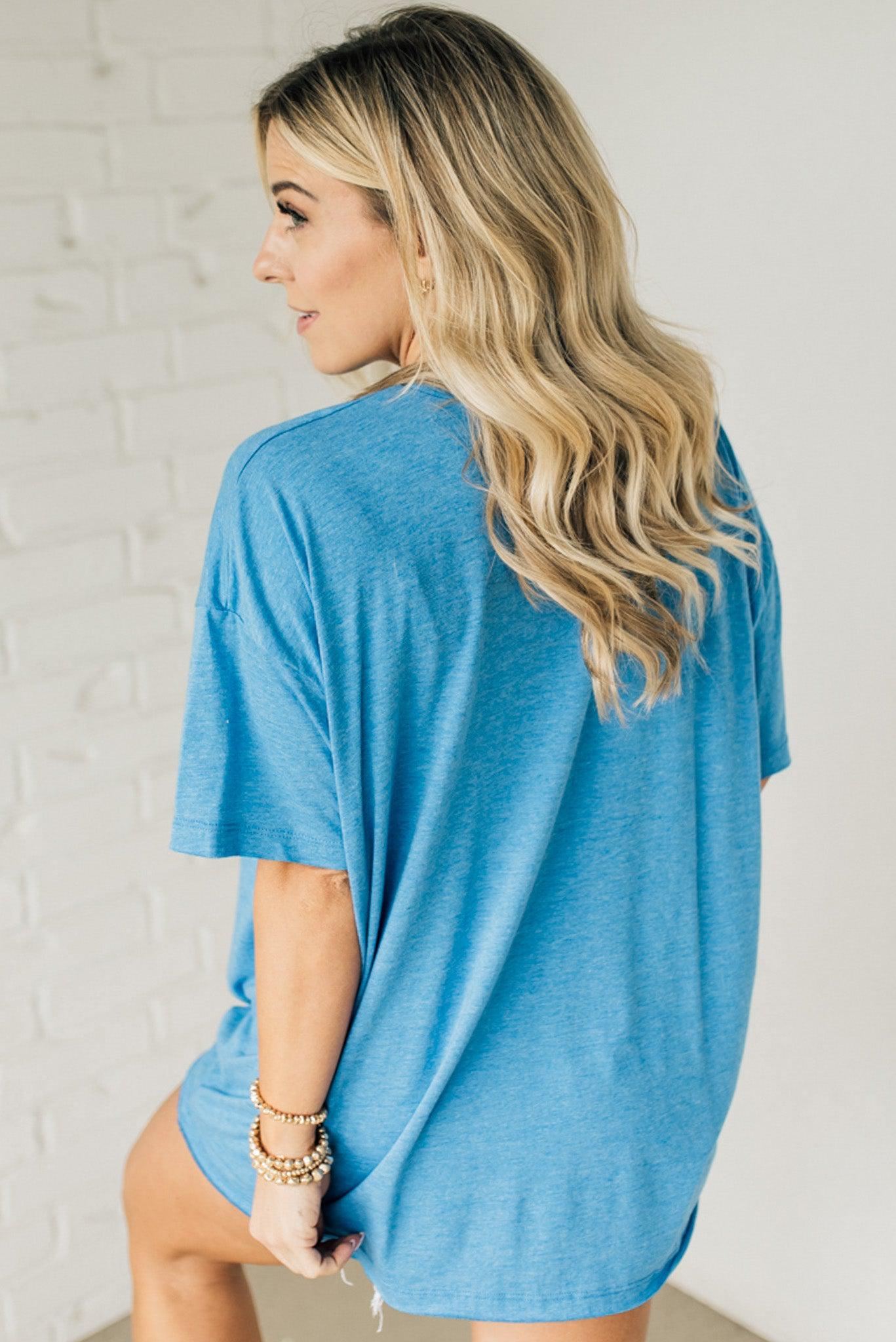 Blonde woman wearing an oversized solid tee with front pocket, and raw scissor cut edges.