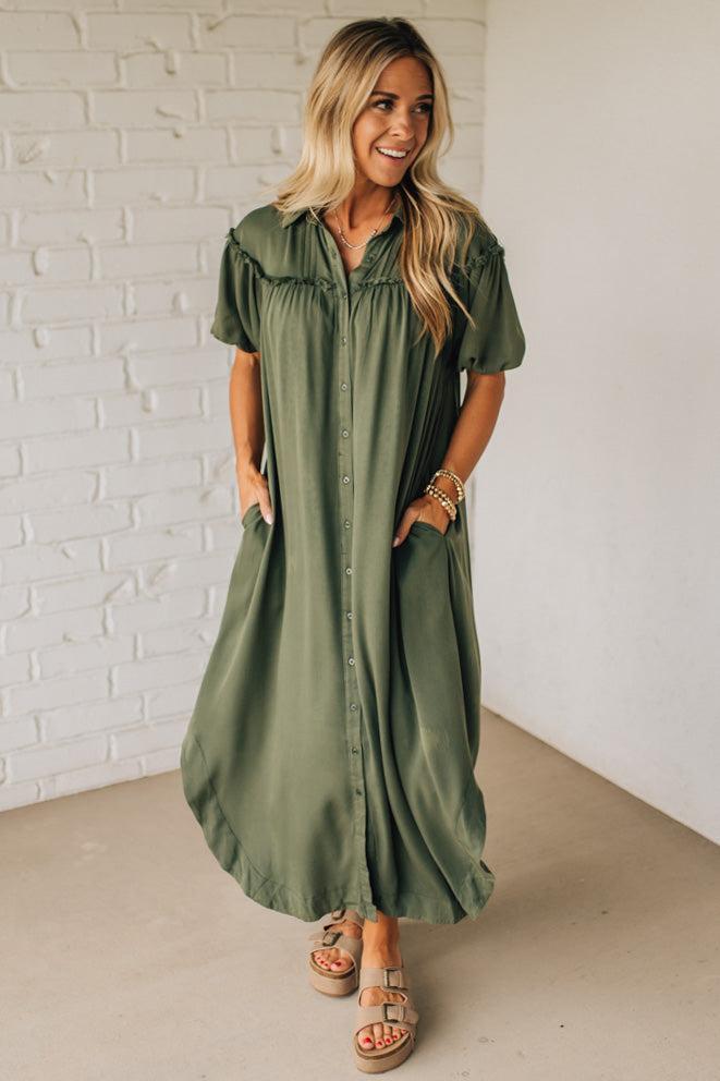 Woman wearing a green dress against a white brick wall.