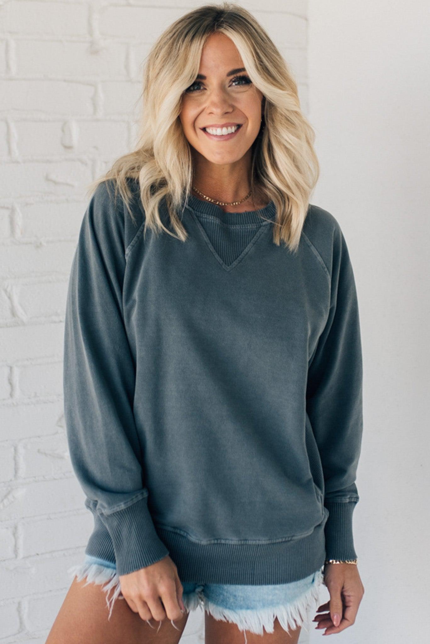 Woman wearing ribbed trim sweatshirt with side pockets.