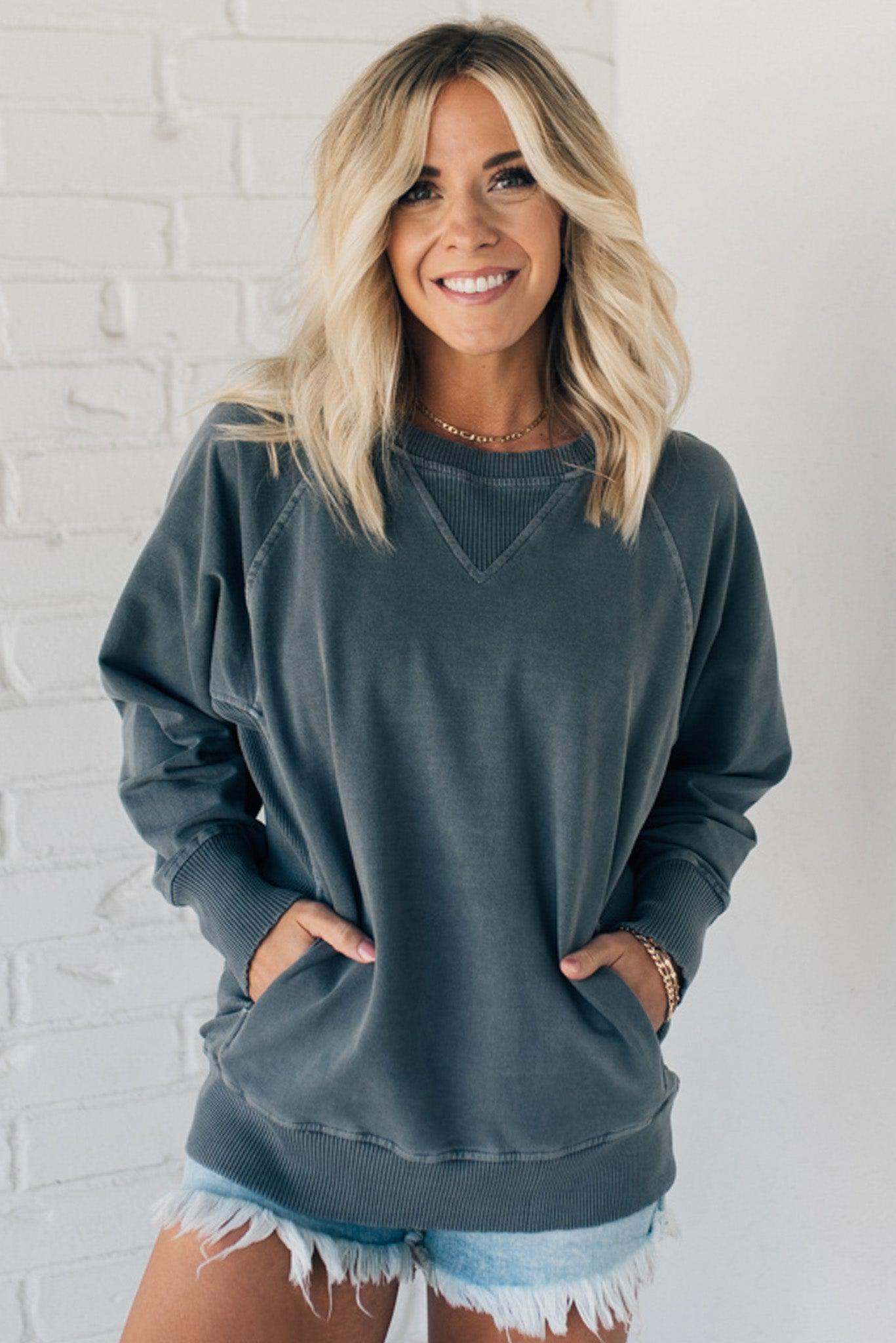 Woman wearing ribbed trim sweatshirt with side pockets.