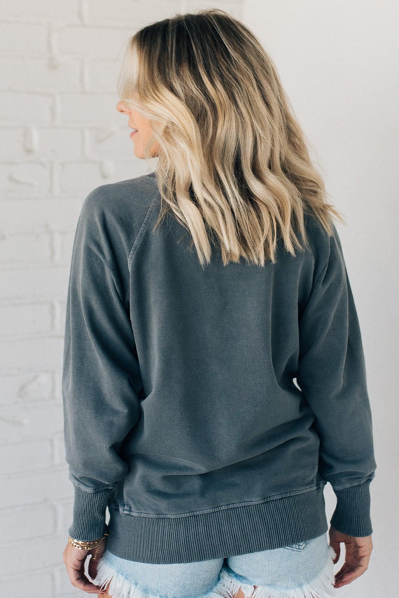 Woman wearing ribbed trim sweatshirt with side pockets.