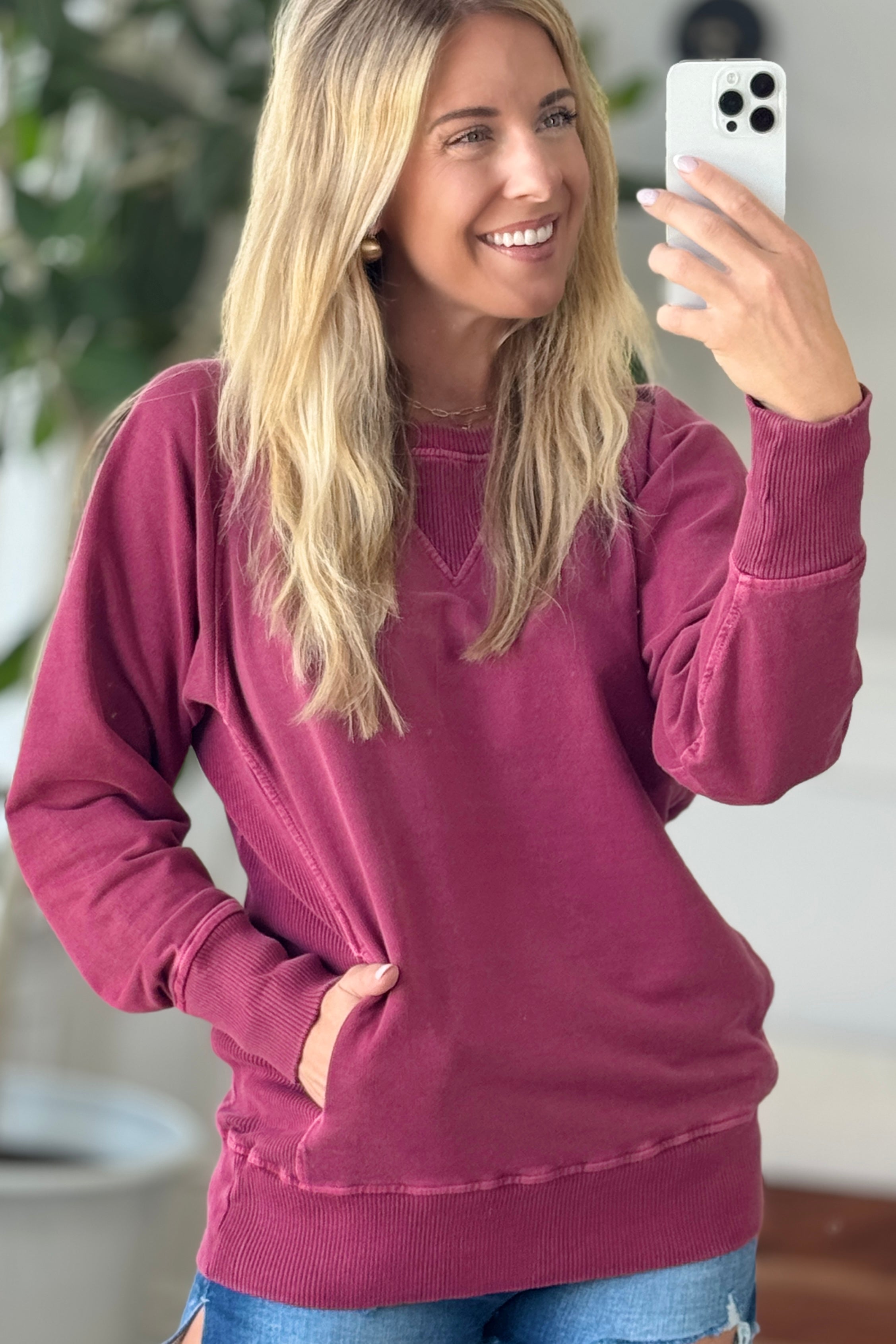 A woman wearing a burgundy ribbed accent pocketed pullover with dolman sleeves and a round neckline.