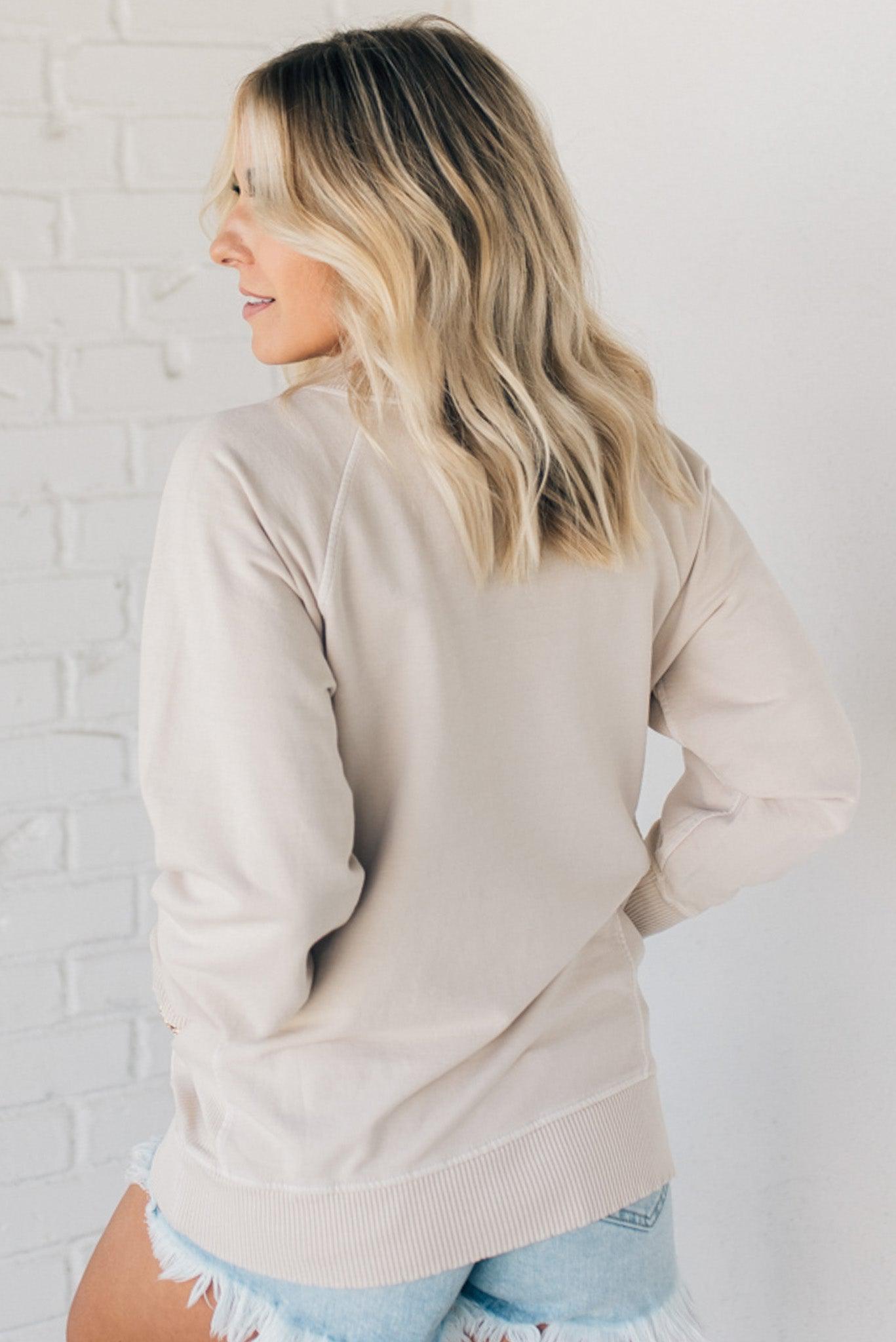 Woman wearing ribbed trim sweatshirt with side pockets.