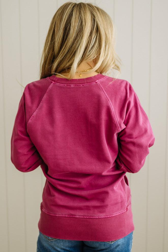 Person wearing a pink sweatshirt from behind with a neutral background