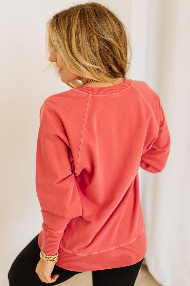 Person wearing a coral sweatshirt against a white background