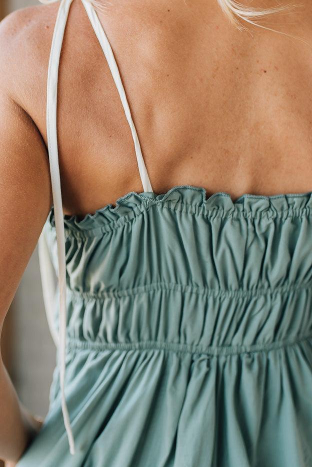 Green dress with white straps worn by a person, focusing on the back and neckline.