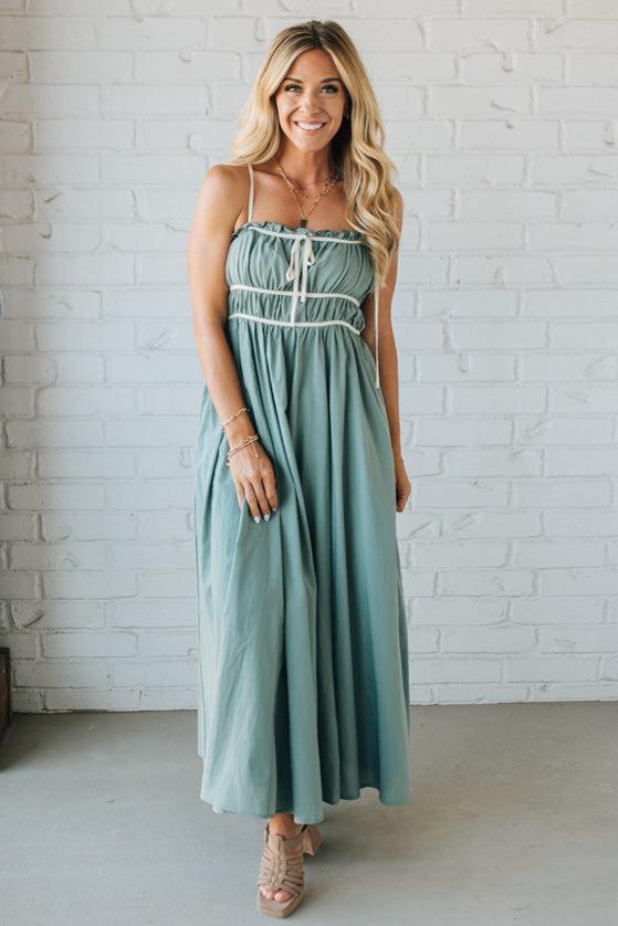 Woman wearing a light blue dress standing against a white brick wall.