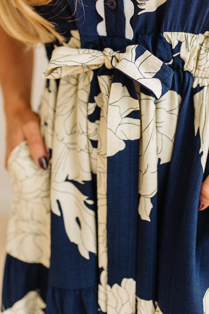 Close-up of a navy and white floral dress with a belt.
