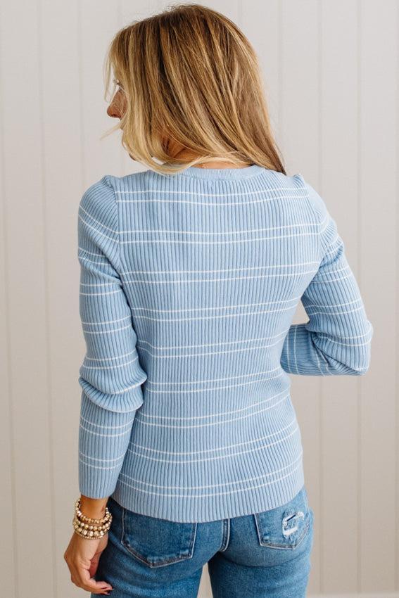BLONDE WOMAN IN A STUDIO WEARING JEANS AND A BIG BELT WITH A BLUE RIBBED, LONG SLEEVE, CREW NECK, SUPER STRETCHY BASIC STRIPED INNER SWEATER.