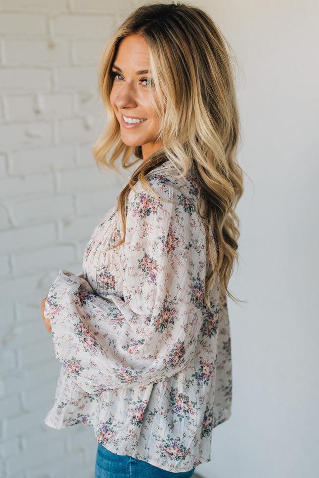 Woman wearing a floral blouse against a white brick wall