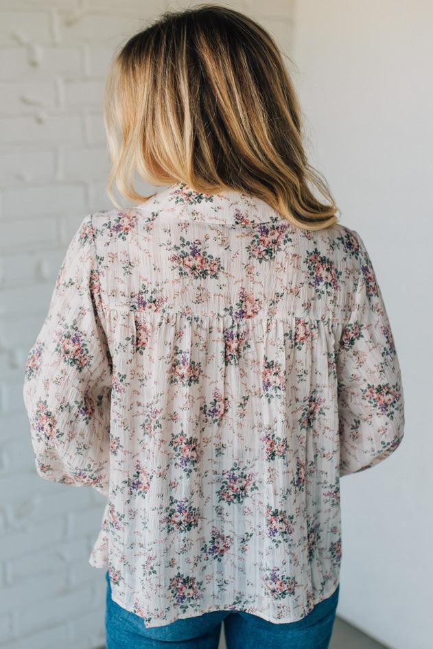 Woman wearing a floral blouse against a white wall