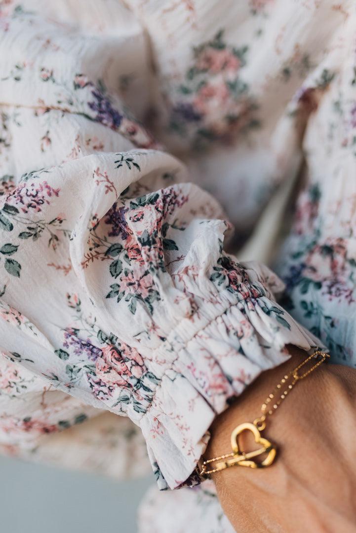 Close-up of floral fabric with a hand wearing a gold bracelet.