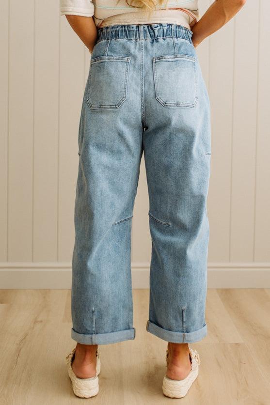 Person wearing light blue jeans standing against a neutral background