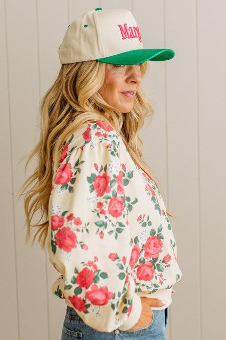 Woman wearing a floral jacket and cap with 'Mary' on a wooden background
