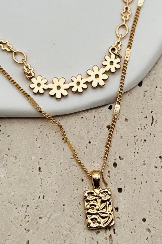 Flat lay of a gold necklace that has two layers with dainty floral details