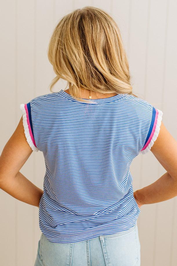 Person wearing a blue striped shirt with pink trim on a plain background