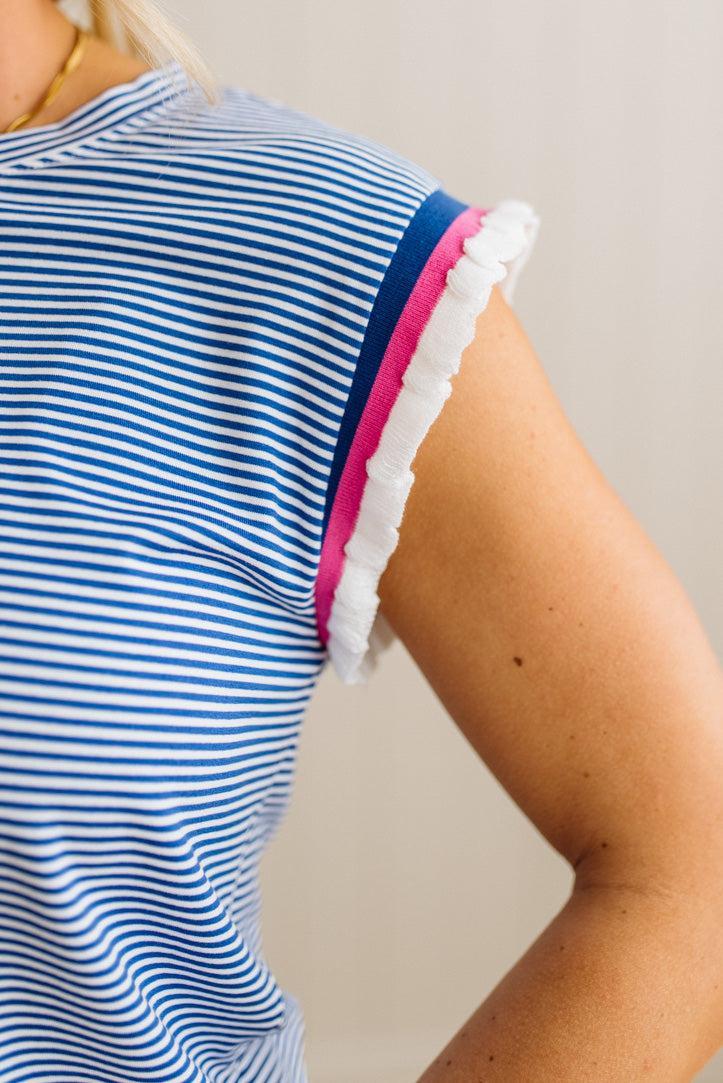 Close-up of a person wearing a blue and white striped top with pink accents.