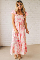Blonde woman wearing a maxi dress with floral pink and a dark pink print, ruffle sleeved, with back smocked panel.