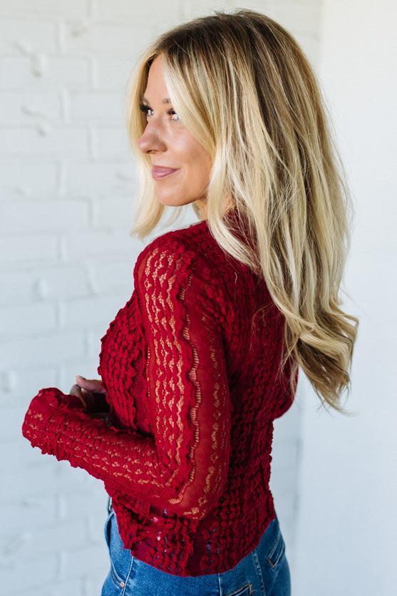 Woman wearing a red mesh lace top against a white background