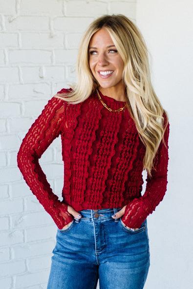 Woman wearing a red mesh lace top against a white background