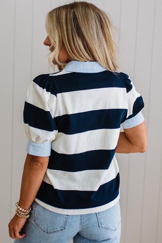 Woman wearing a navy and white striped shirt with a plain background