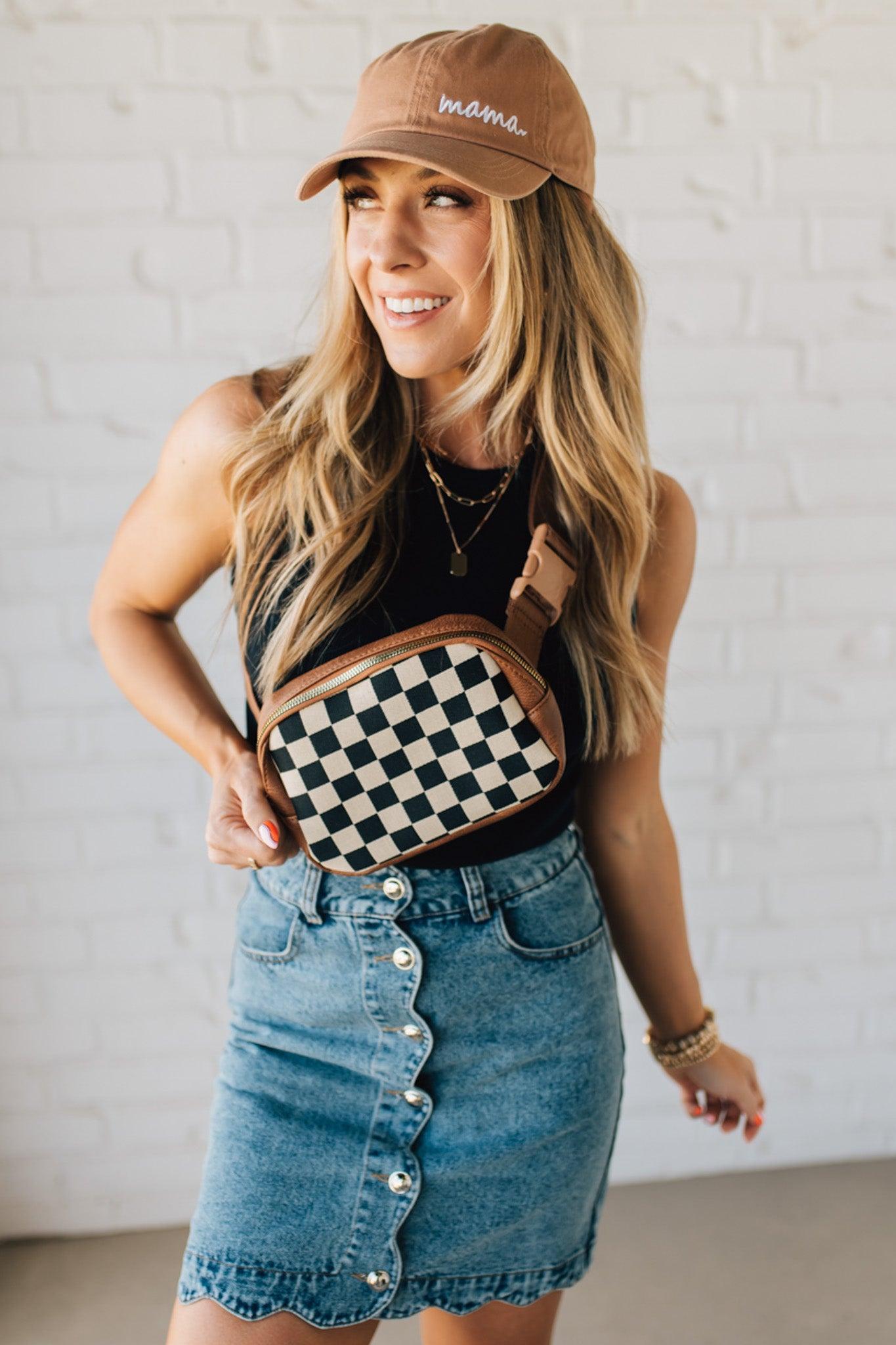 BLONDE WOMAN IN A HAT AND BLACK TANK WEARING A SCALLOP BUTTONED FRONT DENIM SKIRT.