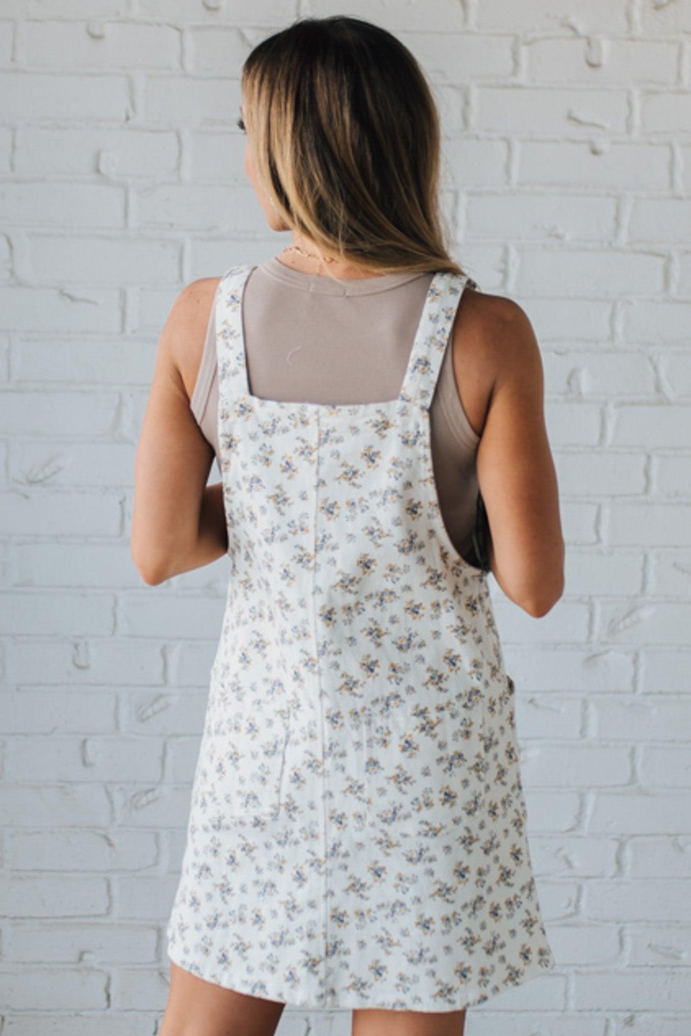 Blonde Woman Wearing a Stretch Ditsy Print Denim Overall Mini Dress in Cream and multi color flowers.