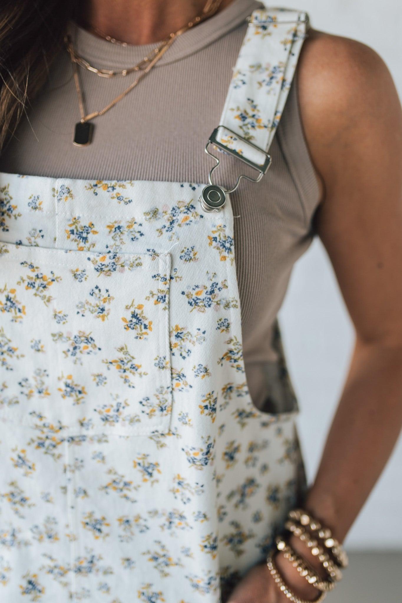 Blonde Woman Wearing a Stretch Ditsy Print Denim Overall Mini Dress in Cream and multi color flowers.