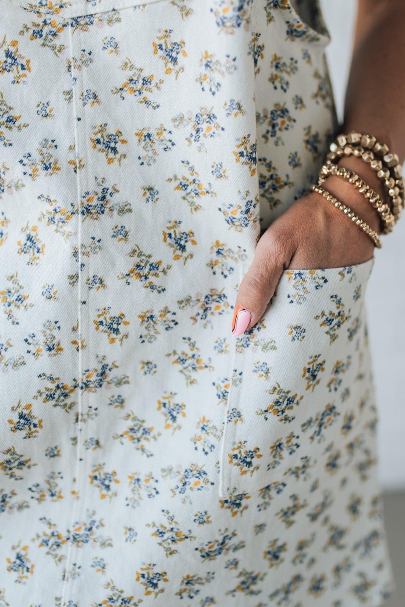 Blonde Woman Wearing a Stretch Ditsy Print Denim Overall Mini Dress in Cream and multi color flowers.