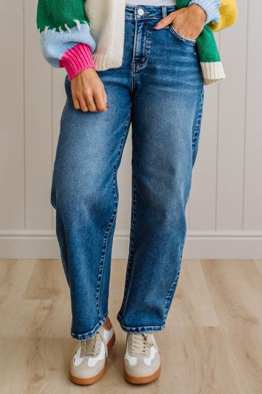 Person wearing blue jeans and a colorful sweater in a neutral setting