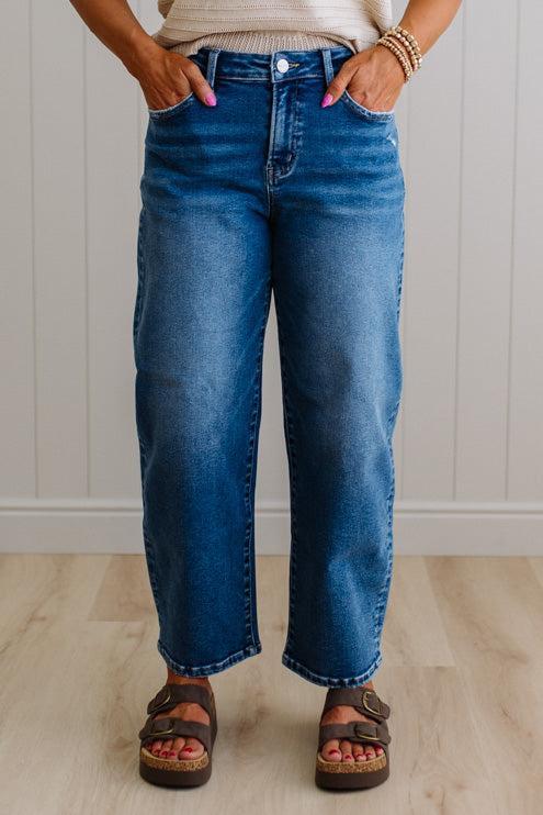 Person wearing blue jeans standing against a white paneled wall.