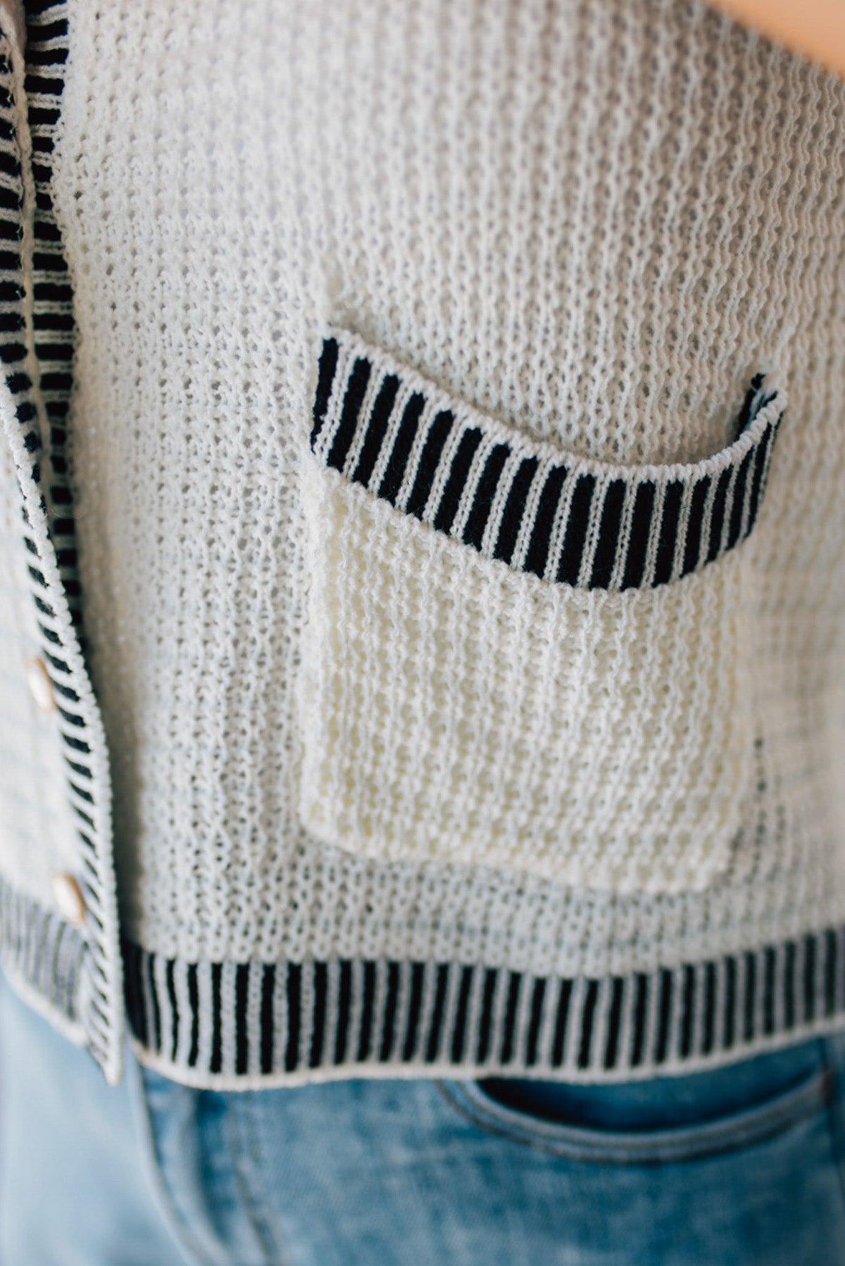 BLONDE WOMAN WEARING A BLACK AND WHITE CONTRAST RIB DETAIL TEXTURED SWEATER VEST WITH PEARL ACCENT BUTTON FRONT.
