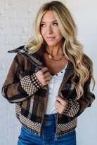 Woman wearing a plaid jacket over a white shirt with a white brick wall background