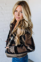 Woman wearing a patterned jacket against a white brick wall