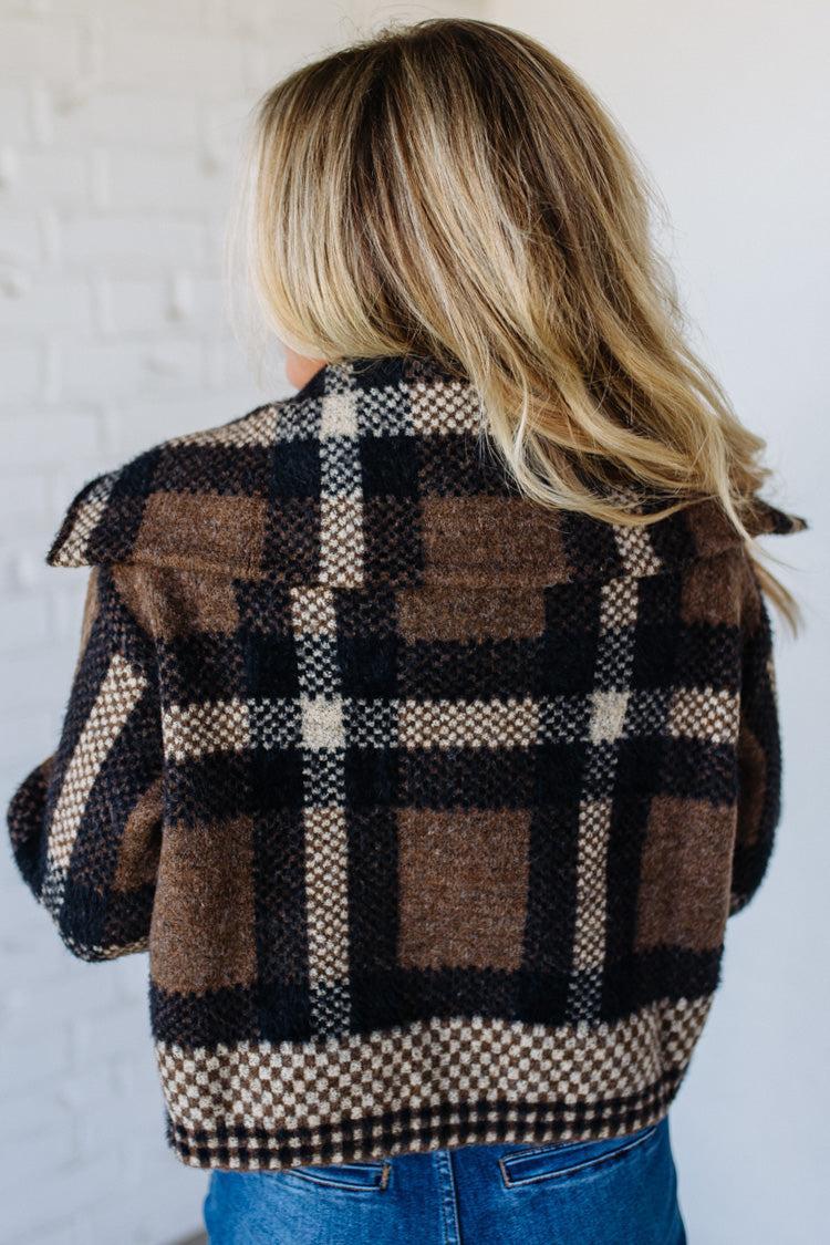 Person wearing a plaid jacket with a neutral background