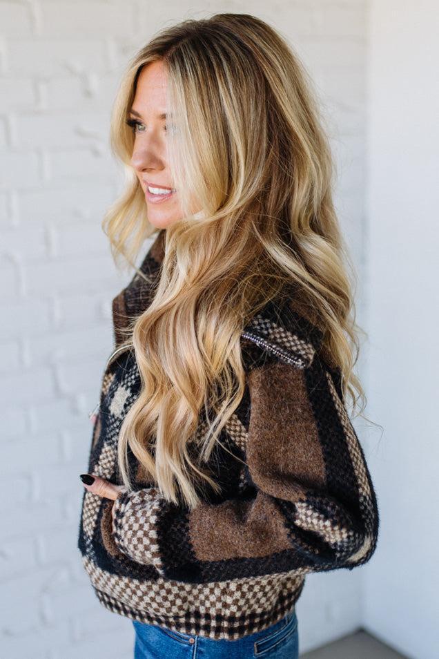 Woman wearing a patterned jacket against a white wall