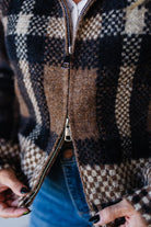 Close-up of a person wearing a plaid jacket with a zipper.