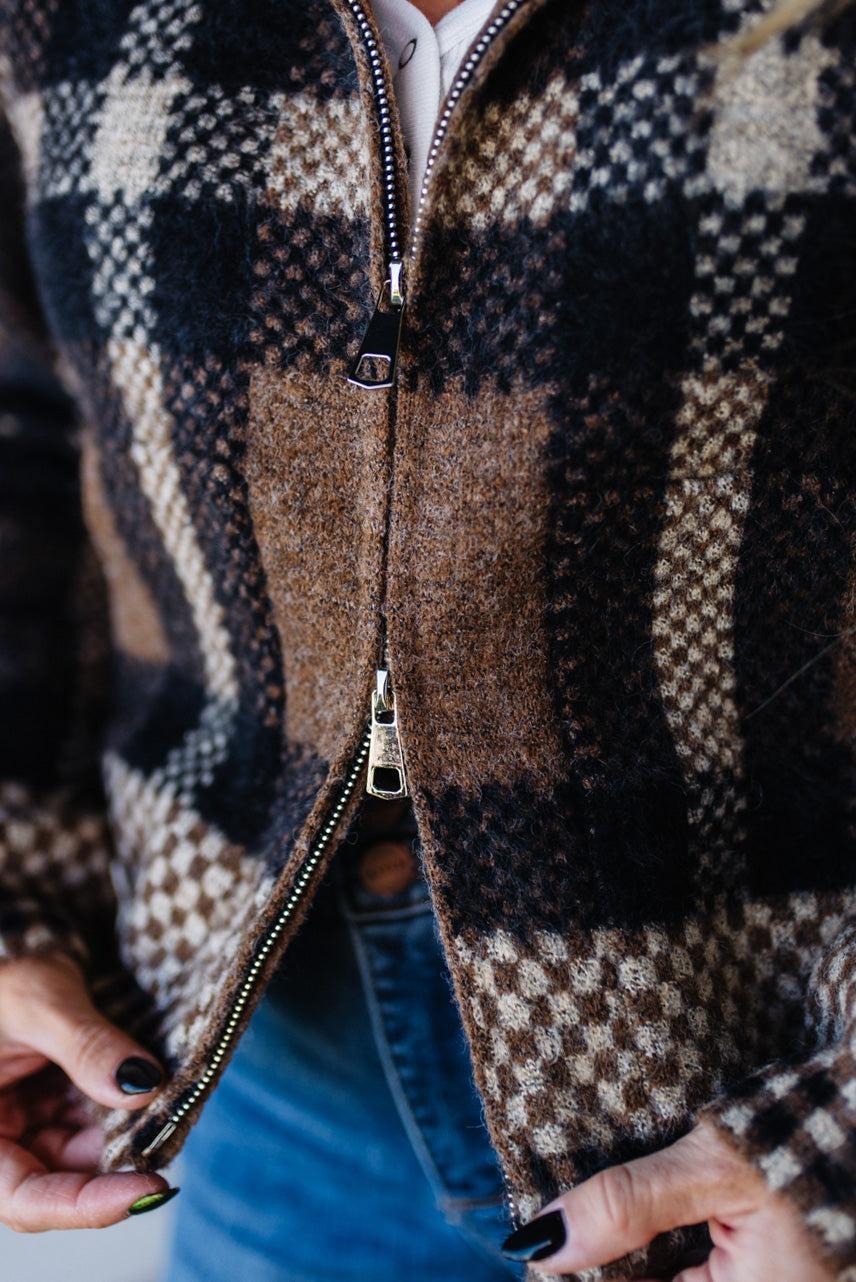 Close-up of a person wearing a plaid jacket with a zipper.