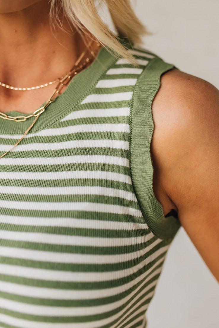 BLONDE WOMAN WEARING A CONTRAST COLOR SCALLOP FINISHED, CREW NECK, SLEEVELESS STRIPED SWEATER.