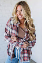 Woman wearing a plaid shirt over a brown top and jeans against a white background