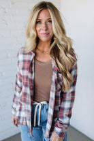 Woman wearing a plaid shirt over a brown top and blue jeans against a white background
