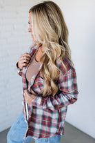 Woman wearing a plaid shirt and jeans against a white wall