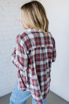Person wearing a plaid shirt and jeans against a white wall