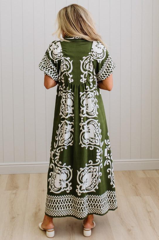 Woman wearing a green dress with white patterns in a minimal indoor setting
