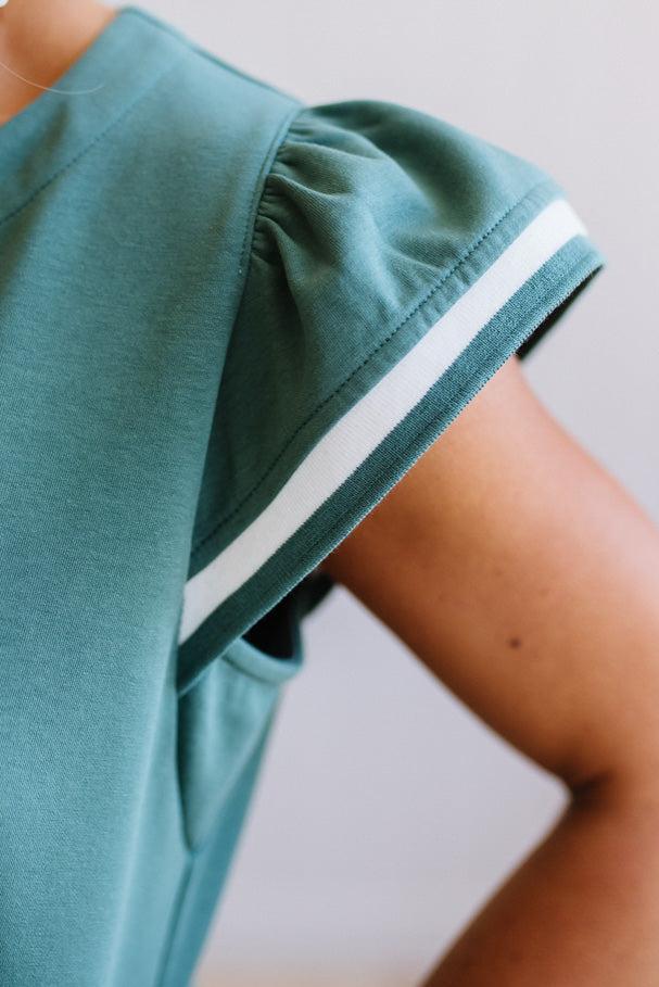 Green athletic outfit with white stripe on a neutral background