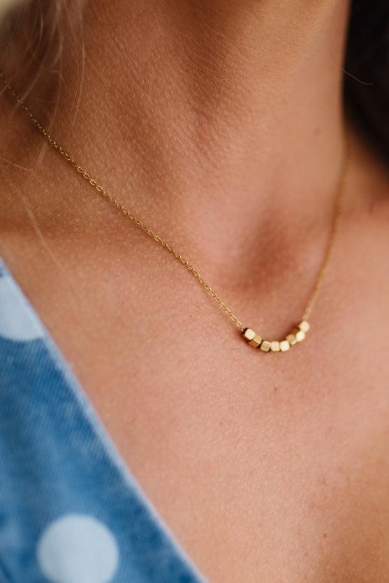 Gold necklace on a person with a blue garment in the background